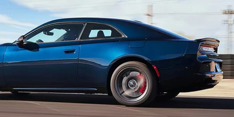A blue 2025 Dodge Charger Daytona EV with sleek lines and red brake calipers, driving on a racetrack.